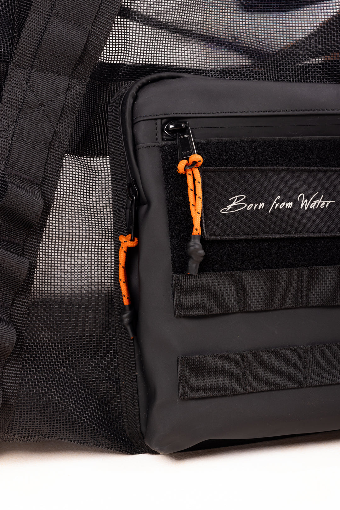 Close-up of a black Waihana gear bag featuring orange paracord zipper pulls, MOLLE webbing straps, mesh side panel, and a &