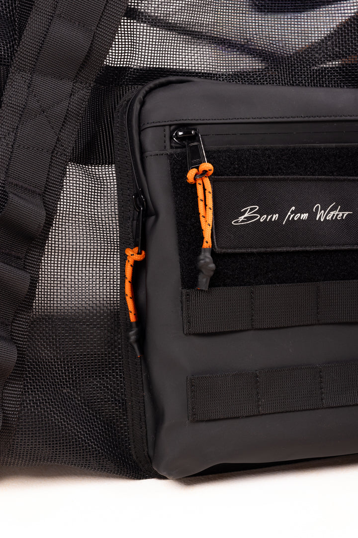 Close-up of a black Waihana gear bag featuring orange paracord zipper pulls, MOLLE webbing straps, mesh side panel, and a &