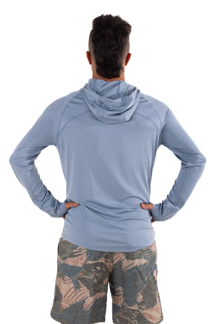 Back view of a man wearing the Waihana Mariner Blue Hooded Long Sleeve Sun Shirt with raglan sleeves, paired with tropical camo board shorts.