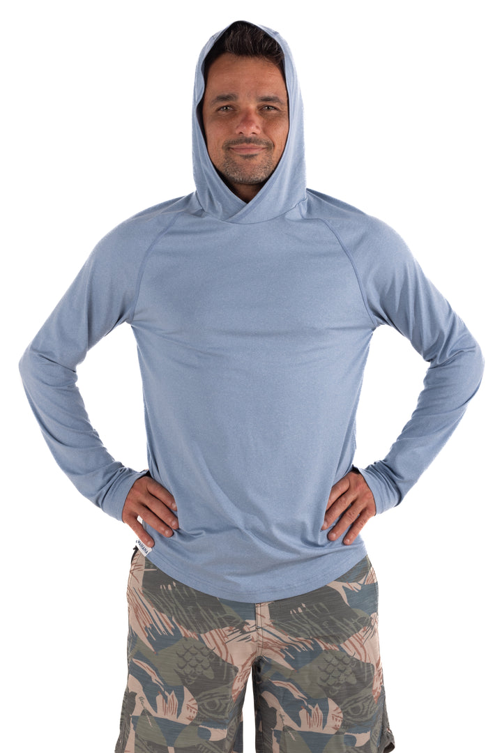 Man wearing the Waihana Mariner Blue Hooded Long Sleeve Sun Shirt with camo board shorts, hands on hips, front view on white background.