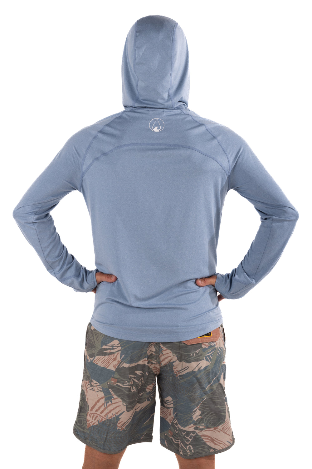 Back view of a male model wearing the Waihana Mariner Blue Hooded Long Sleeve Sun Shirt with Waihana logo on the upper back, paired with tropical camo board shorts.