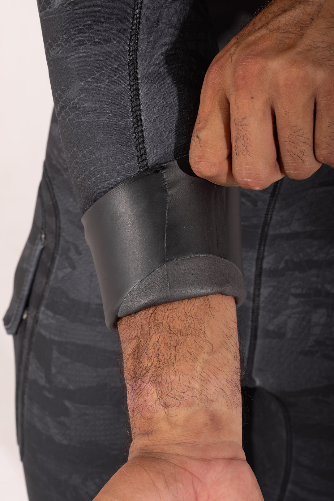 Close-up of a man pulling back the smooth rubber wrist seal cuff of the Waihana Men&